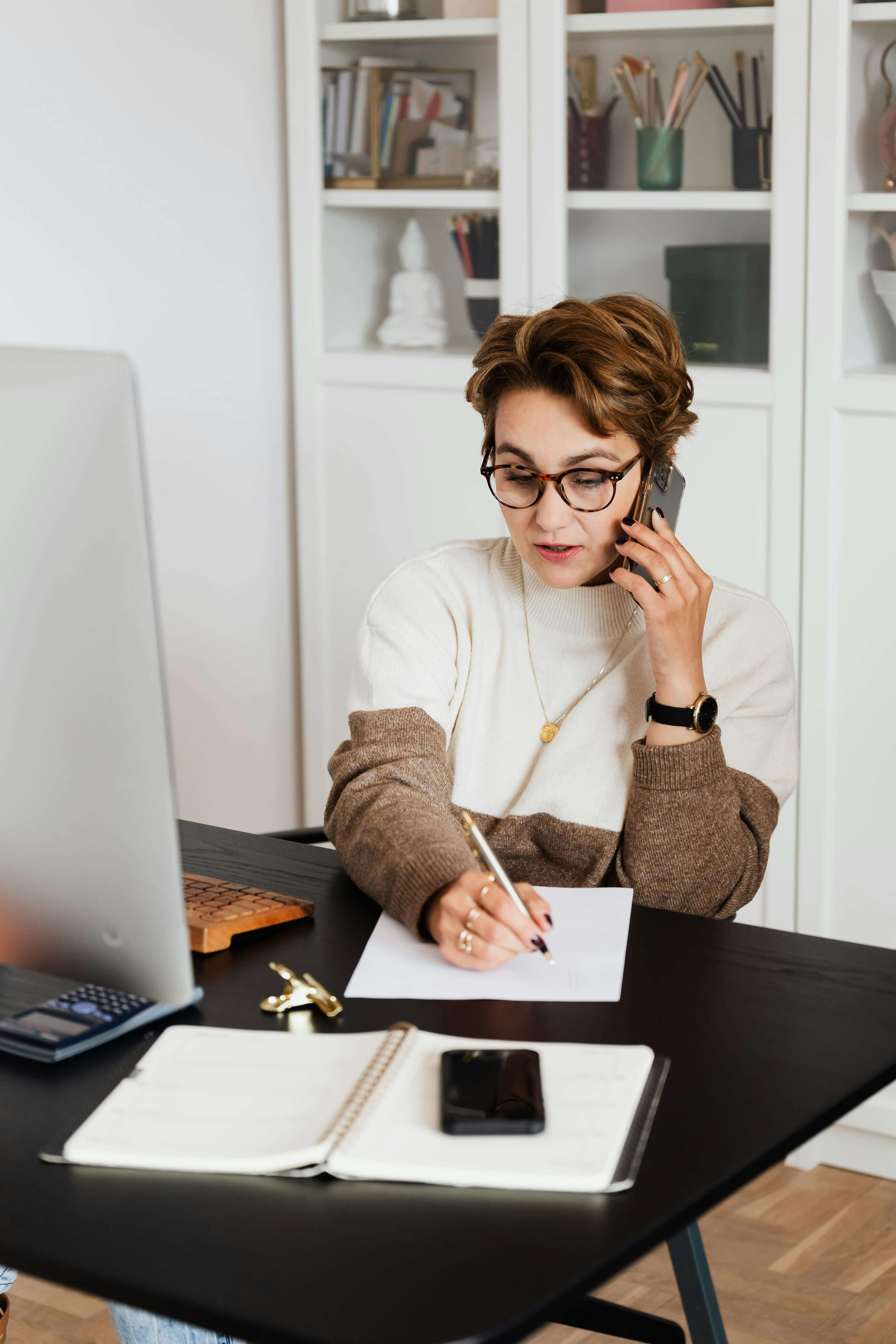 Lady on phone, working in front of computer